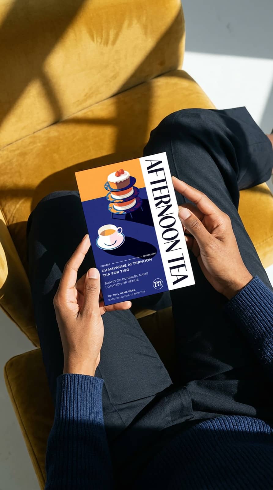 A personalised afternoon tea gift voucher keepsake ticket by Momeo held in hand.
