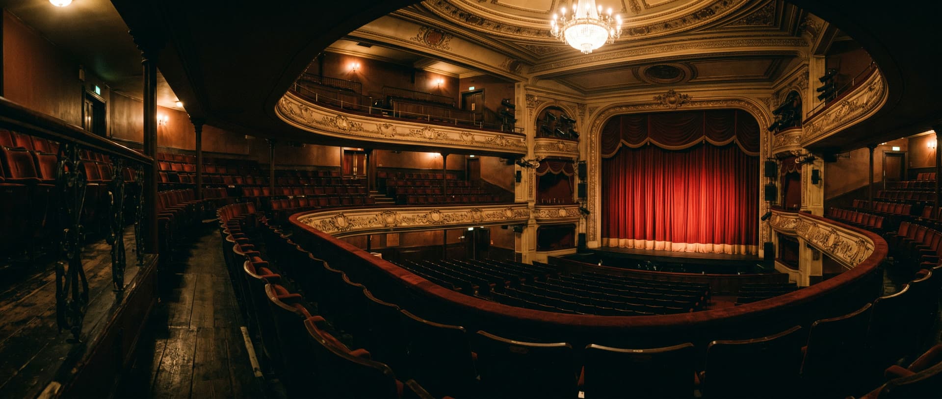 A West End theatre auditorium with red velvet seats and the curtain lit before a show — Momeo personalised keepsake gift